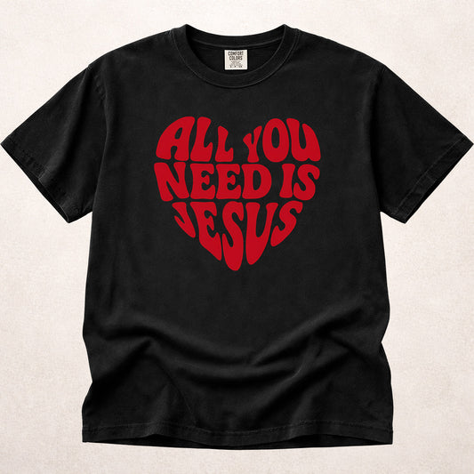 Black (Black) Comfort Colors® 1717 tee with All You Need Is Jesus text in a heart shaped layout.