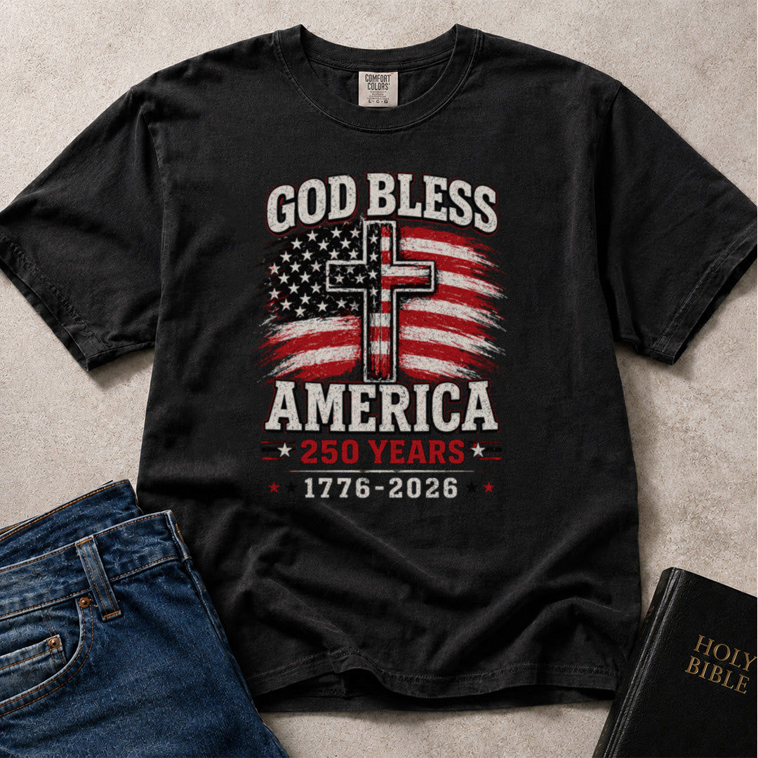 Black Comfort Colors® 1717 Christian patriotic graphic t-shirt featuring God Bless America text, an American flag cross design, and a 250 Years 1776–2026 anniversary message.