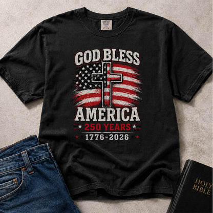 Black Comfort Colors® 1717 Christian patriotic graphic t-shirt featuring God Bless America text, an American flag cross design, and a 250 Years 1776–2026 anniversary message.