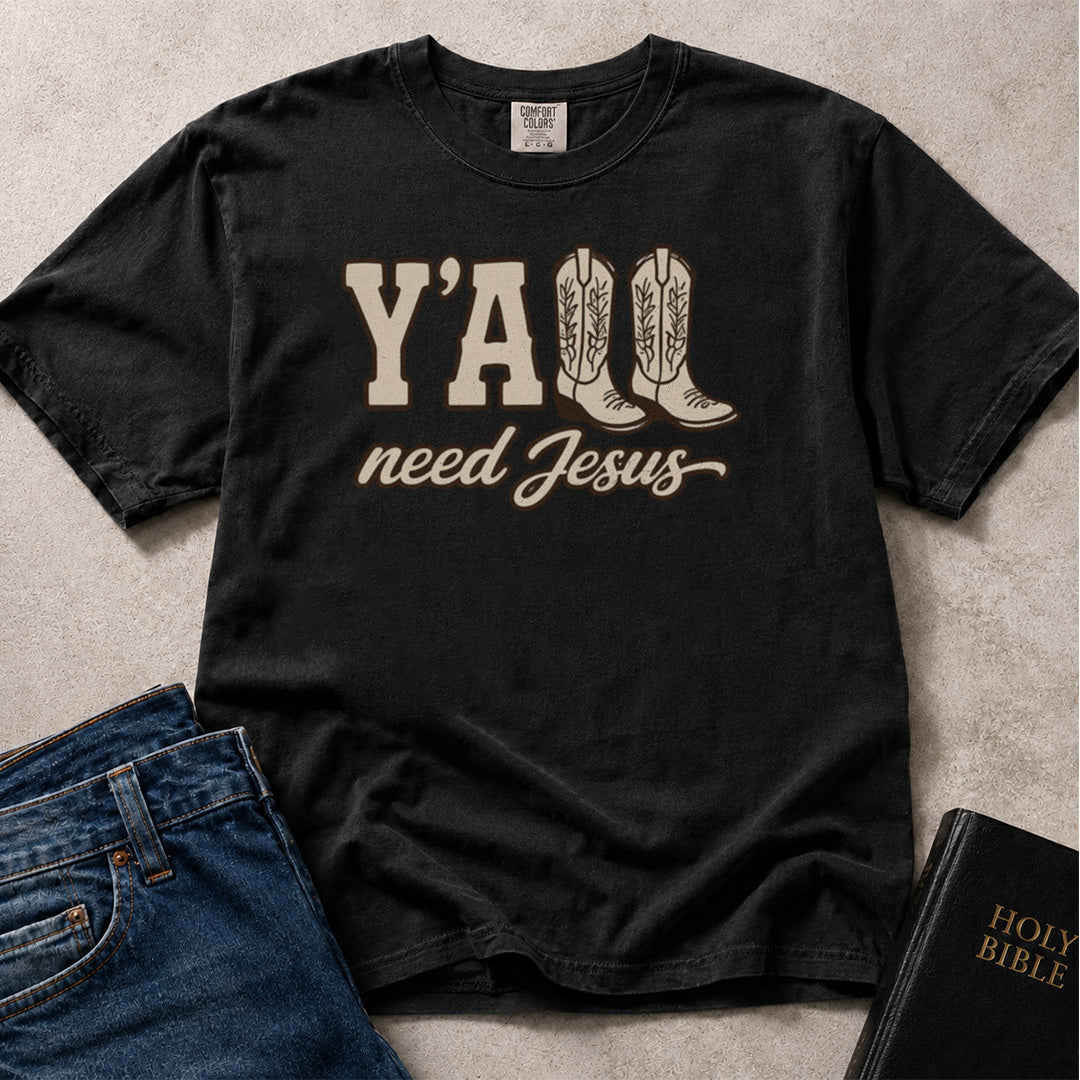Black Comfort Colors® 1717 t-shirt featuring a graphic Y'all Need Jesus Southern faith-inspired design with cowboy boots illustration.