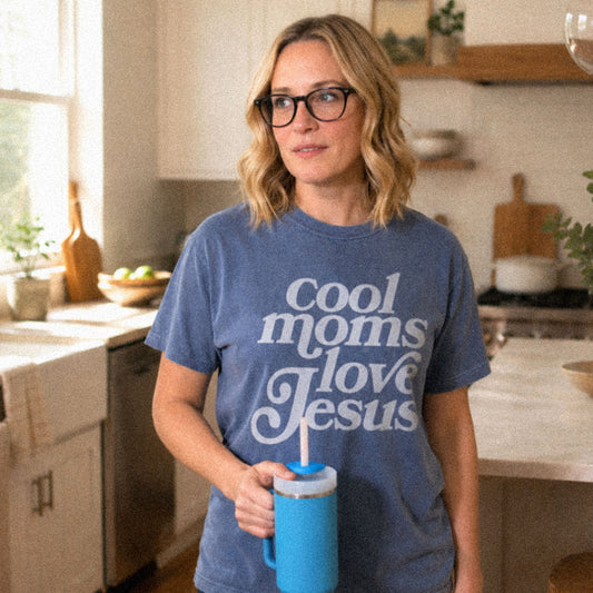 Woman in kitchen wearing blue (Blue Jean) Comfort Colors® 1717 t-shirt with text that reads Cool Moms Love Jesus.