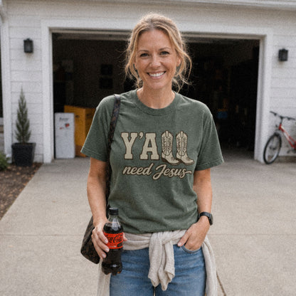 Woman on driveway wearing green (Moss) Comfort Colors® 1717 tshirt featuring a faith-inspired Y'all Need Jesus graphic with a Southern cowboy boots design.